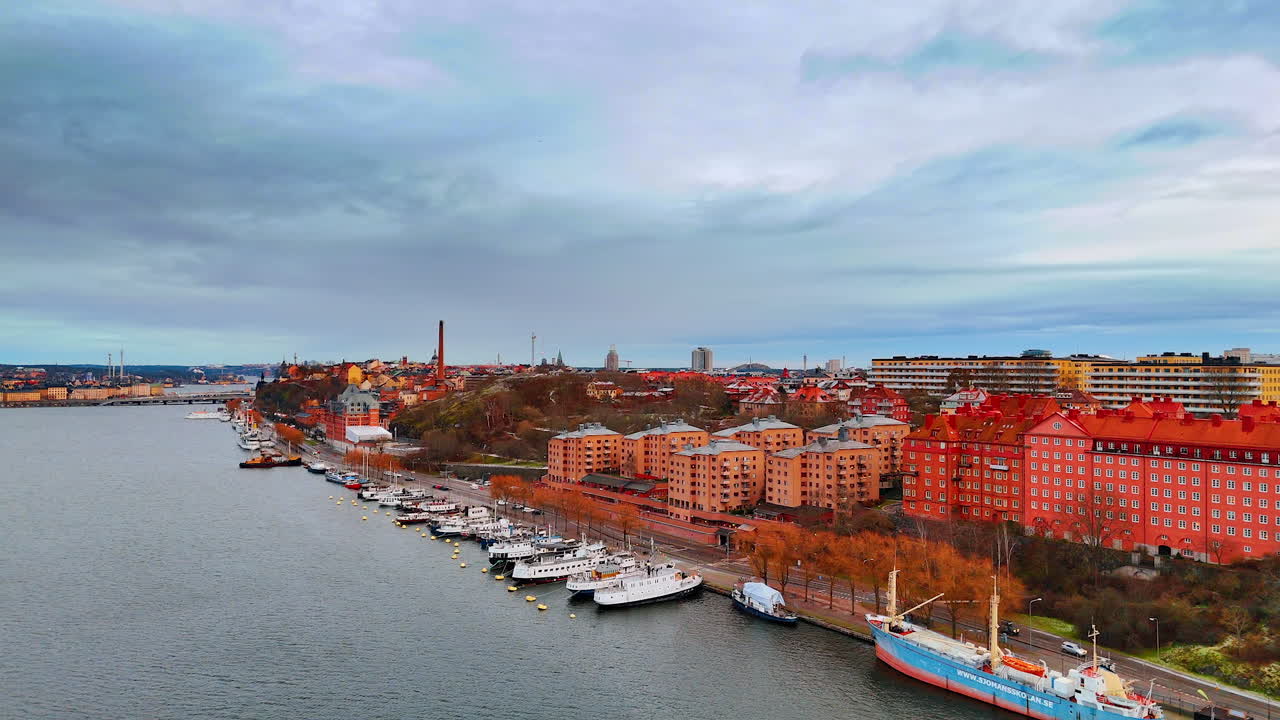 Vista della città con barche lungo il fiume ed edifici rossi sulla riva. Vista di un fiume con diverse barche ormeggiate lungo la riva