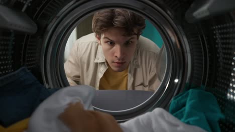 man inspecting laundry in a washing machine