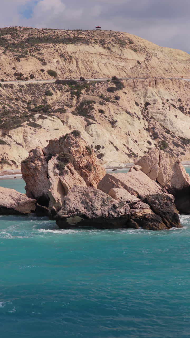 Aerial drone view of Aphrodite's Rock near Paphos, Cyprus, surrounded by turquoise Mediterranean waters. Vertical