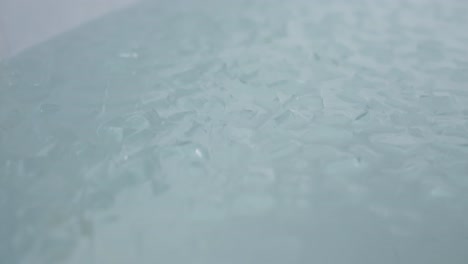 a bath full with ice cubes shaking, close up