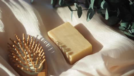 natural soap bar and hairbrush with eucalyptus on light fabric
