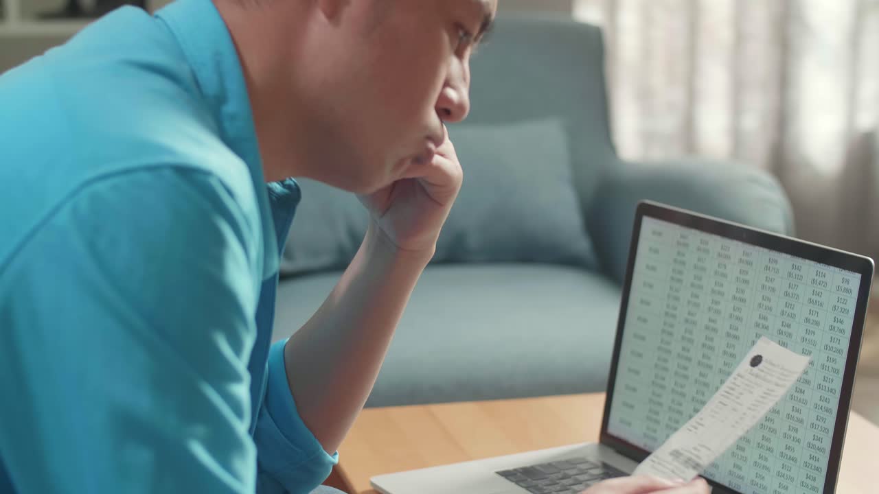 노트북을 들고 계좌를 보고 재정 문제로 인해 두통을 고 있는 아시아 남성의 가까운 측면 시각