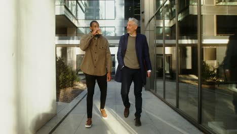 two businessmen walking and talking in an office courtyard