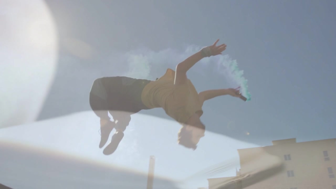 Actor holding smoke can steadying on ledge leaping backward flipping landing low making blue trail