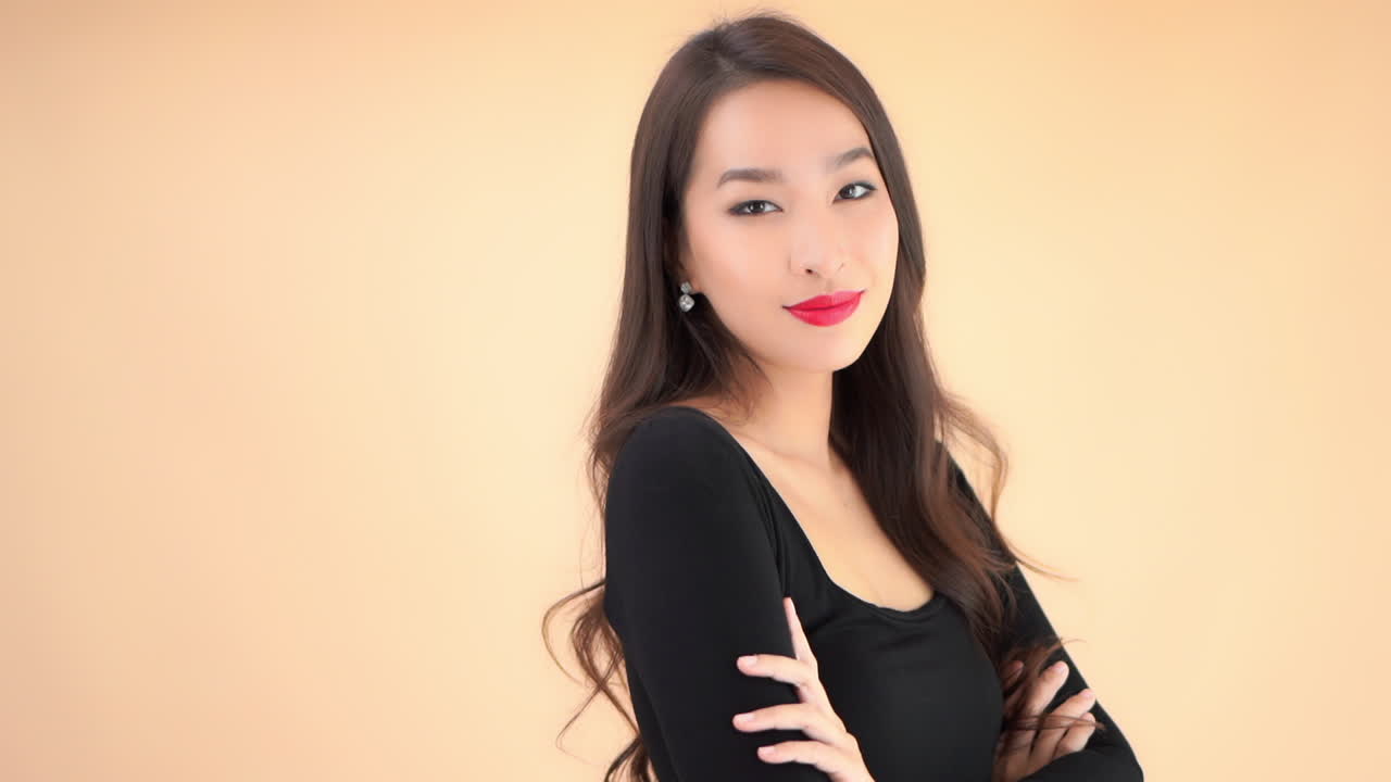 Close up of a stunning young woman pushing her long brown hair away from her eyes while crosses her arms across her chest