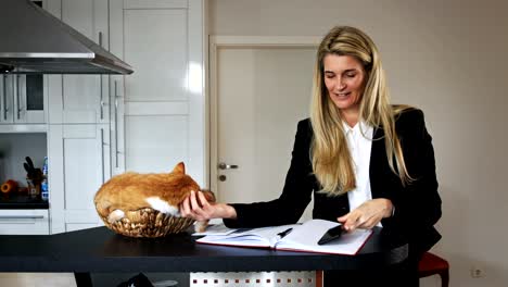 mujer de negocios jugando con un gato en una canasta y hablando por teléfono