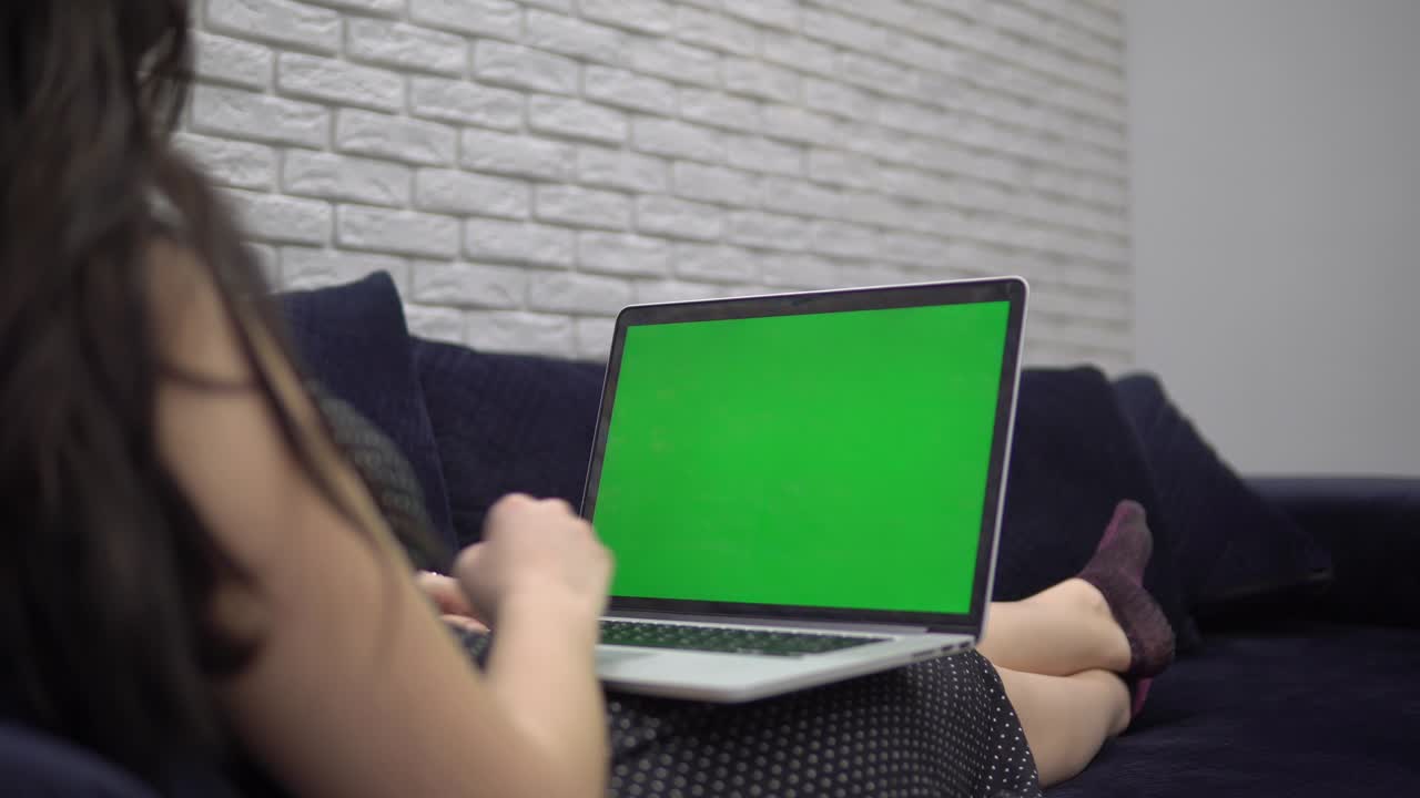 laptop green screen mockup, woman using laptop on sofa at home