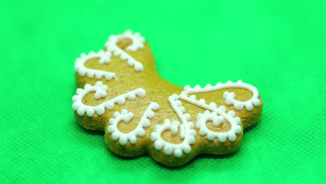 zoomed in a gingerbread pastry with white decorations on top in the shape of a christmas moon on a green background