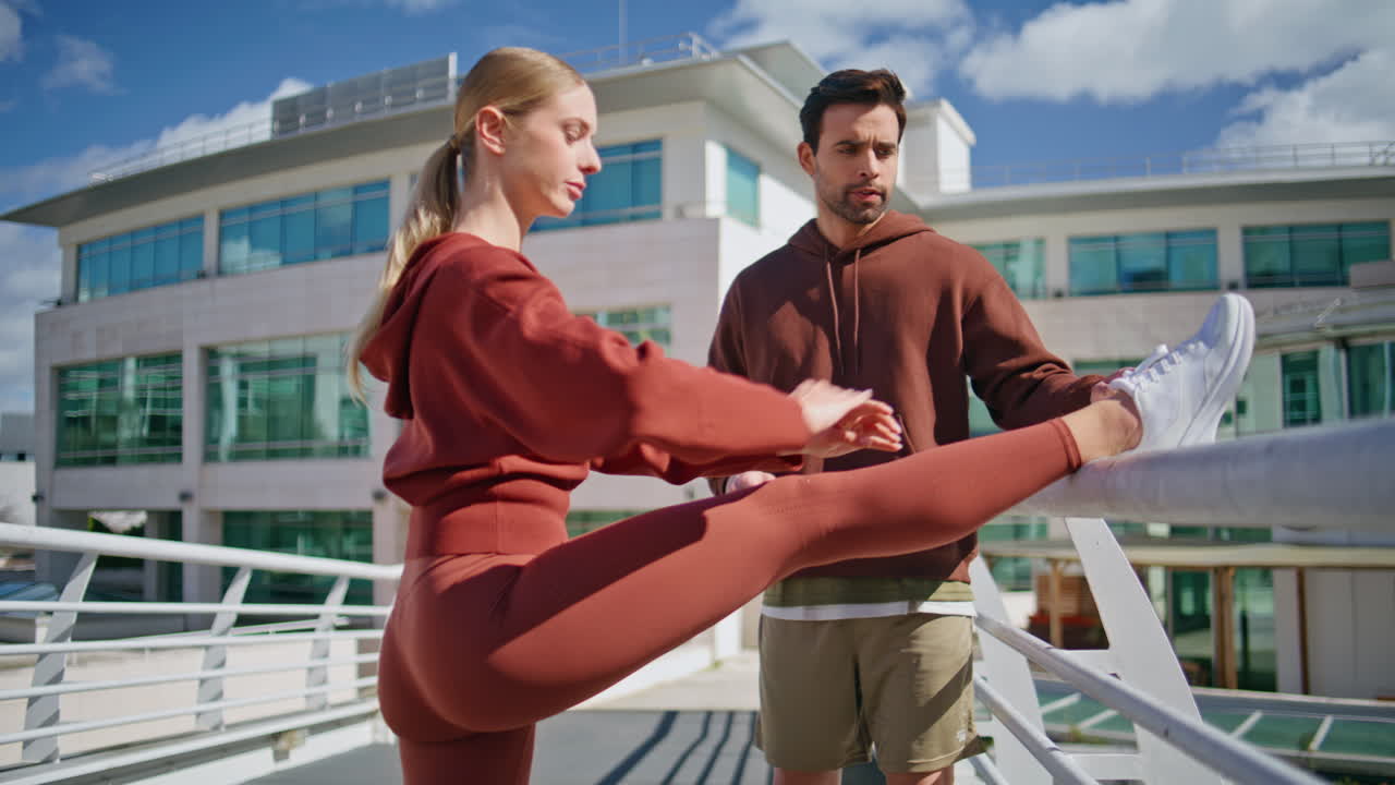 Fit athlete stretching muscles legs before running. Sport coach assisting woman