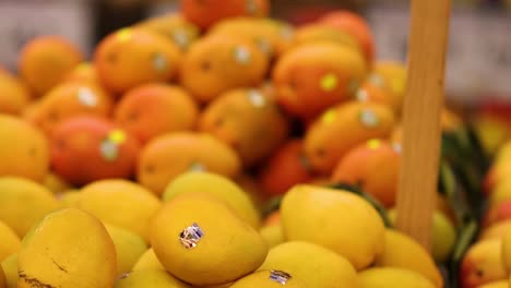 a person reaches for lemons in a vibrant fruit display, showcasing fresh produce selection.