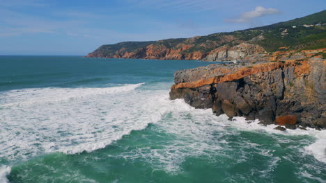 sea hitting rugged coastal cliffs sunny day. rough ocean waves rolling to rocks.