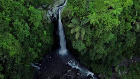 Vista-Aérea-De-Drones-Volando-Sobre-La-Naturaleza-Ver-Un-Río-Que-Termina-En-Una-Cascada-Con-Vegetación-Circundante