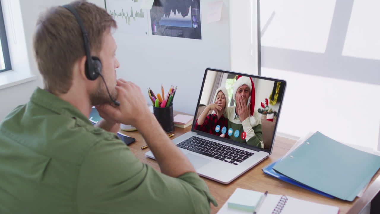 Kaukasisk mand bruger bærbar computer på videochat med venner i julen derhjemme.