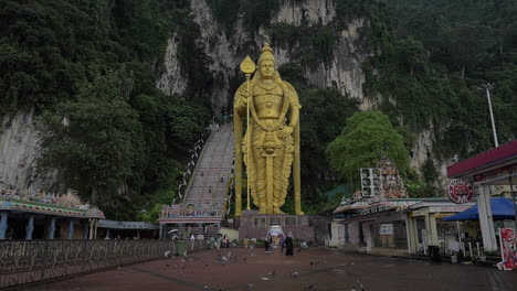 Zeitlupenclip-Fliegender-Tauben-Im-Vordergrund-Und-Murugan-Goldstatue-Gegen-Felswand-Gombak-Selangor-Malaysia