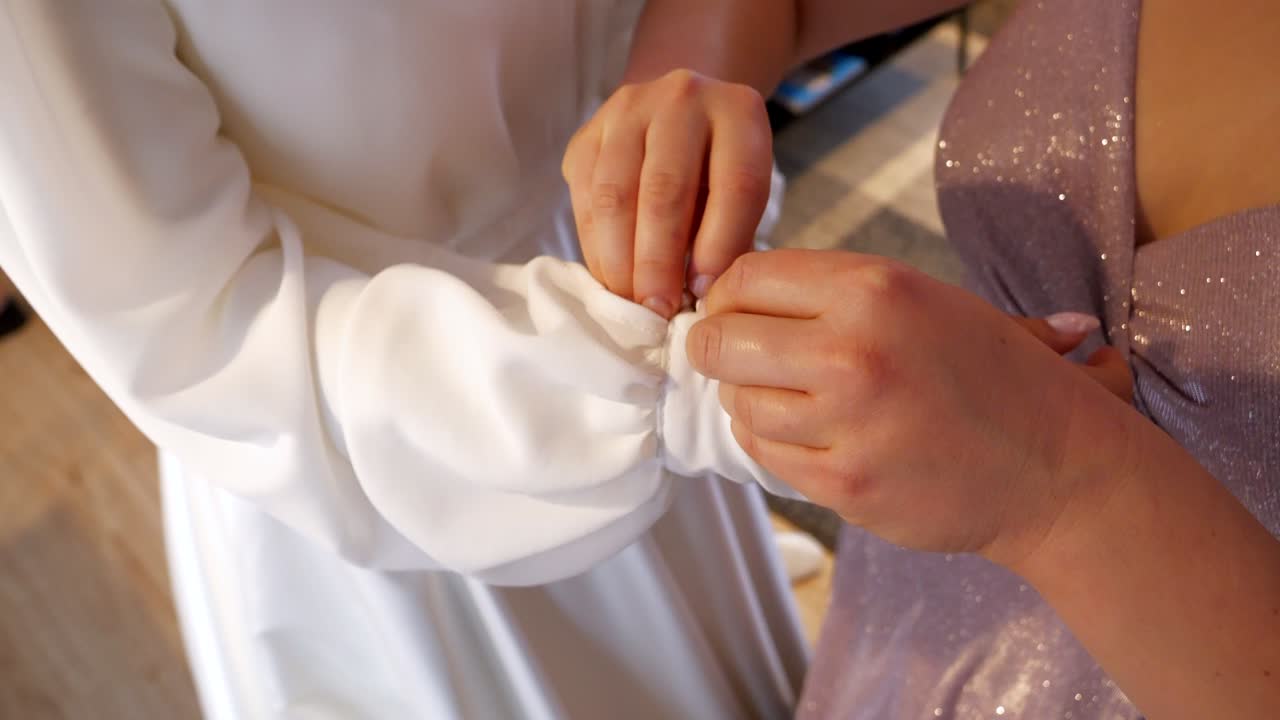 Fastening decorative buttons on a white wedding gown