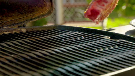 placing a raw steak on a hot grill