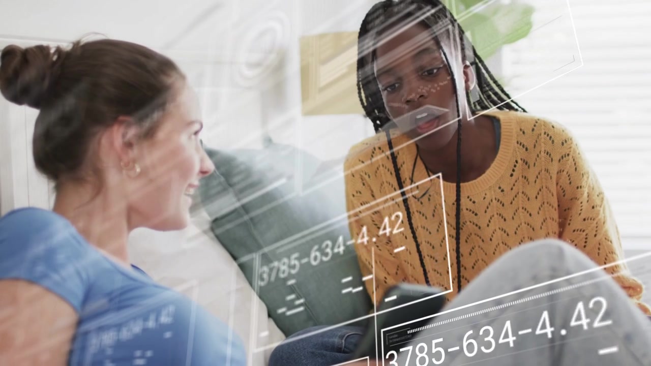 Girl in blue tapping screen, causing floating data overlays while peer leaning analyzing tech data