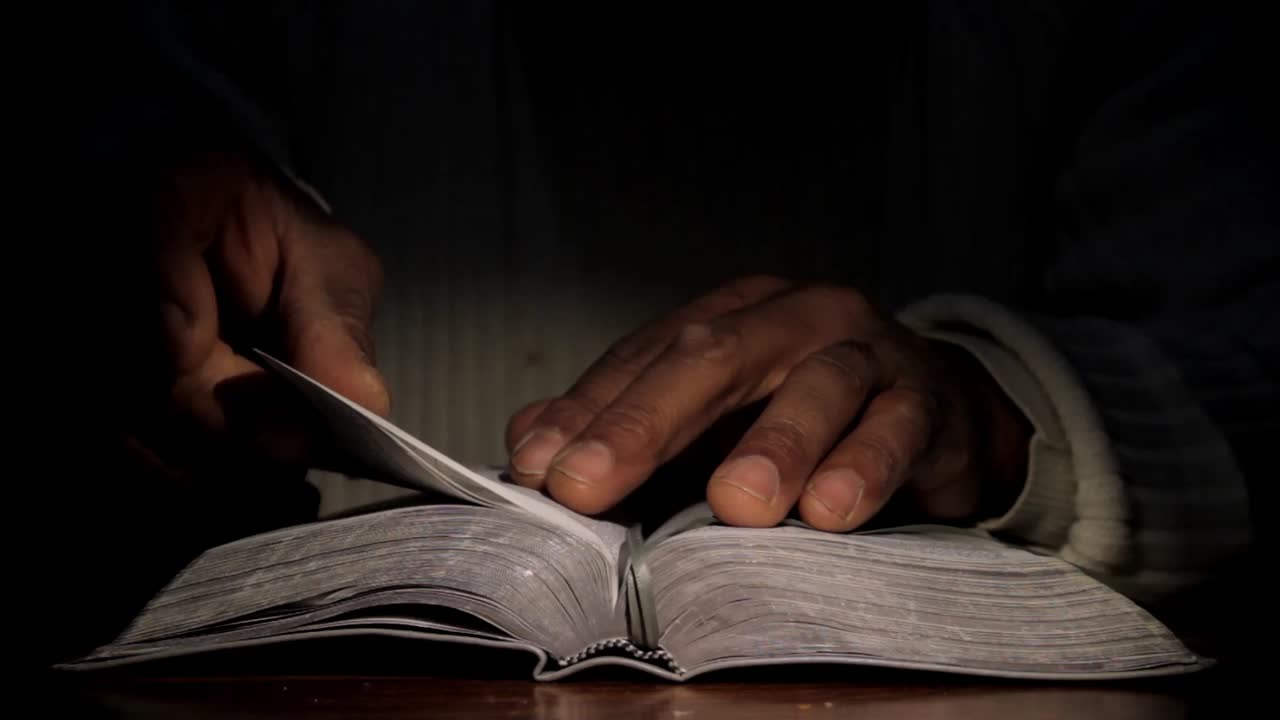 hombre negro rezando y leyendo la biblia en una mesa almacen de metraje de video