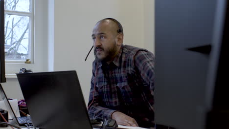 Smiling-businessman-wear-wireless-headset-making-conference-video-call-on-laptop