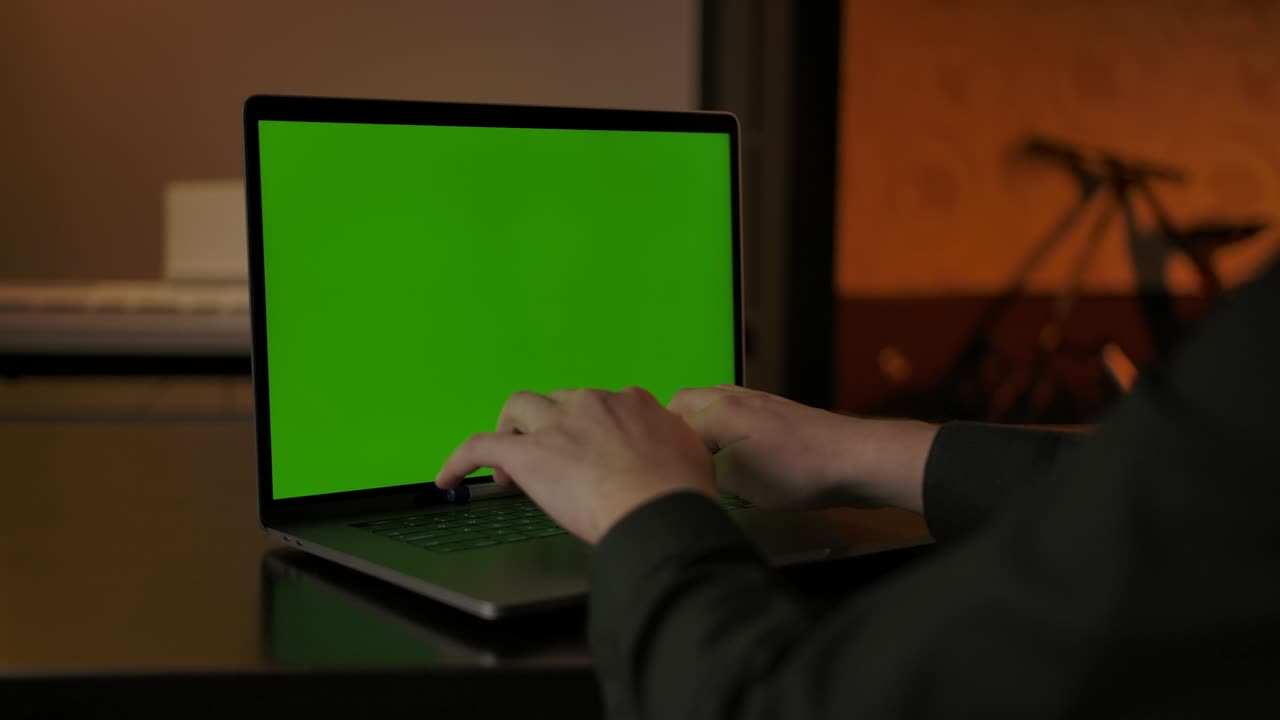 hombre sin rostro irreconocible escribiendo algo en una computadora portátil de pantalla verde