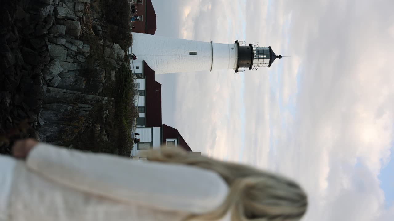 una mujer rubia de pie y mirando el faro de portland head en cape elizabeth, maine, estados unidos