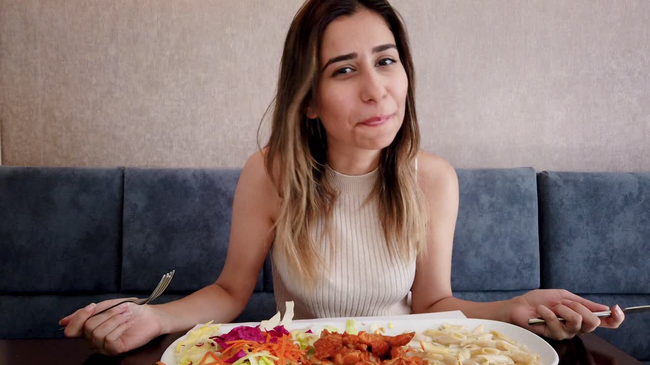 una joven hermosa come pollo con un gran disfrute en un restaurante o cafetería mientras está sentada