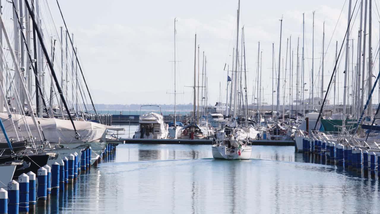 Sailboat yacht depart docks cruising on calm sea water, medium shot