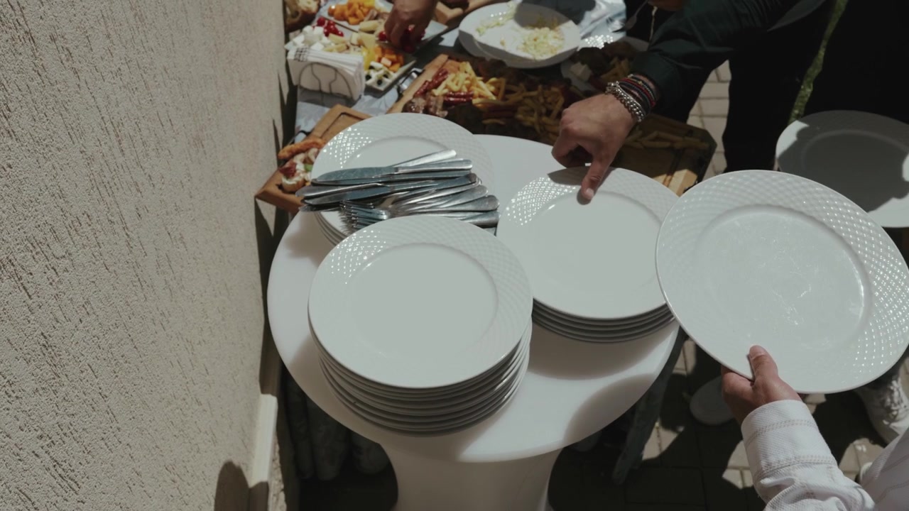 A man holding clean plates at a wedding buffet before guests begin dining. Elegant catering setup at a wedding reception.