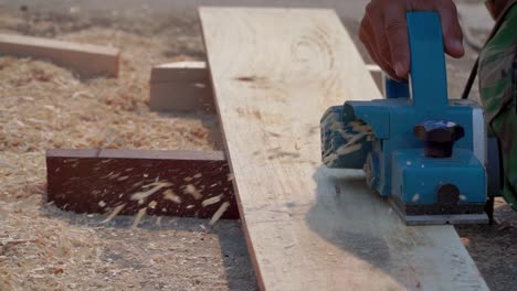 close up shot hand of carpenter using planer machine to smooth the surface