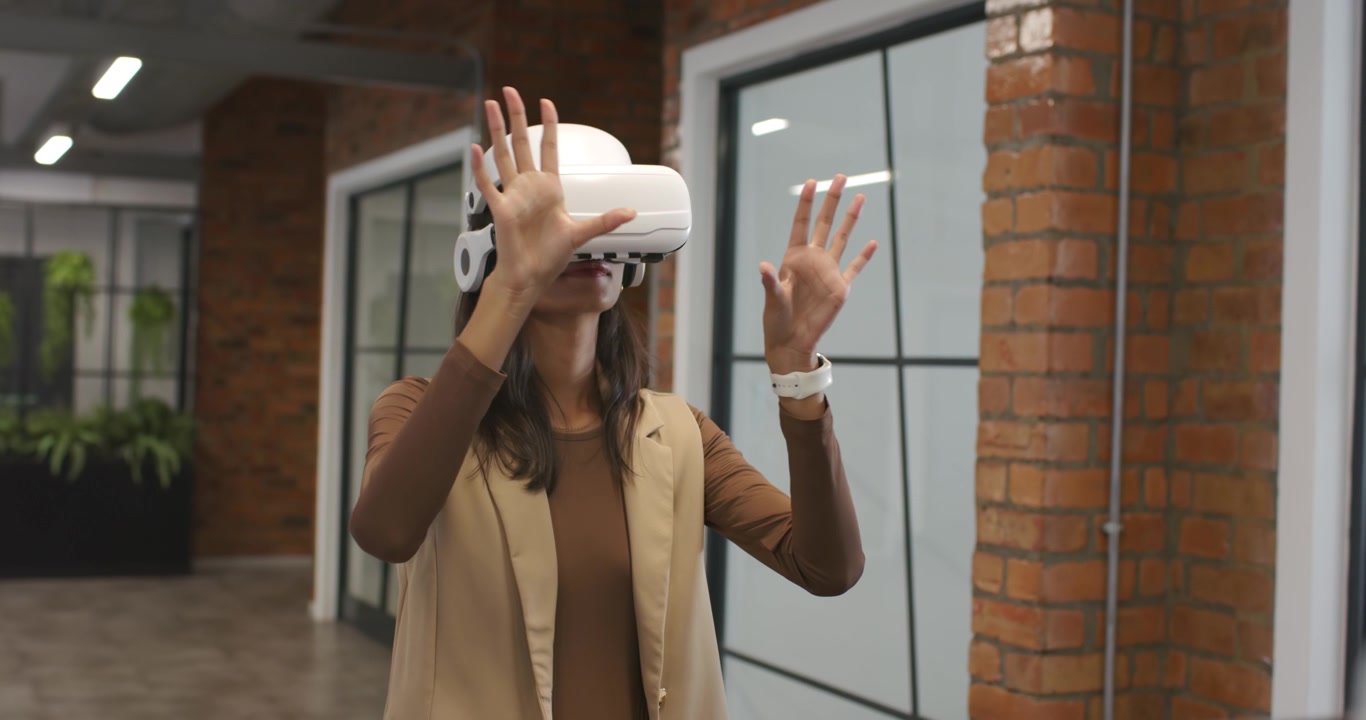 Donna afroamericana che alza la mano, pizzica e tocca, testando i controlli di un visore VR in ufficio