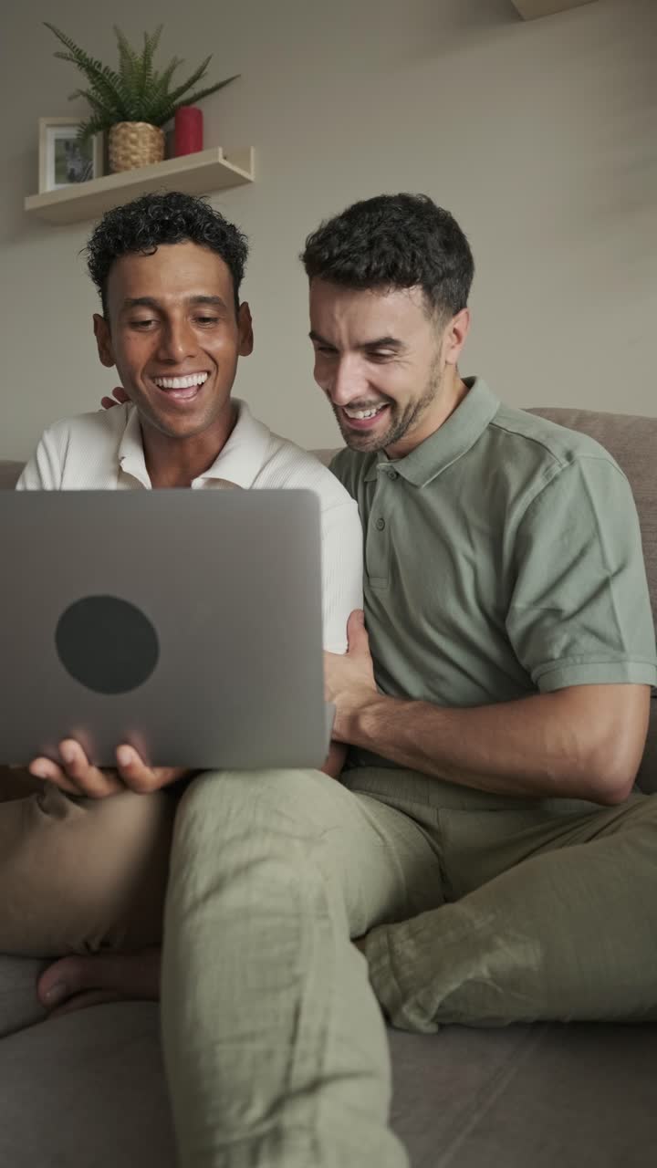 Two men using a laptop on the couch