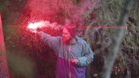 hombre sosteniendo una llamarada roja en un bosque