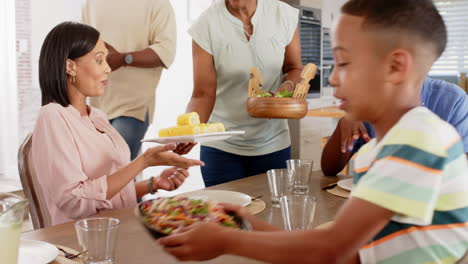 A diverse family enjoying meal together, with children passing dishes to adults