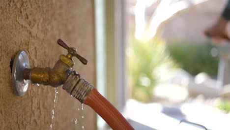 Turning-on-a-hose-faucet-to-water-the-garden-but-wasting-water-as-it-is-spraying-and-leaking