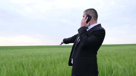 a farmeragronomist in business clothes speaks aggressively on a mobile phone businessman inspects his land a farmeragronomist in business clothes speaks aggressively on a mobile phone