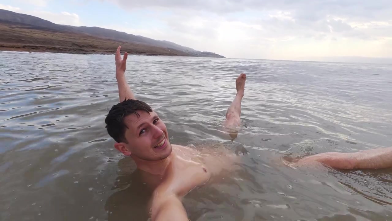 Un uomo galleggia senza sforzo nel Mar Morto altamente salino in Giordania mentre si filma con una action cam.