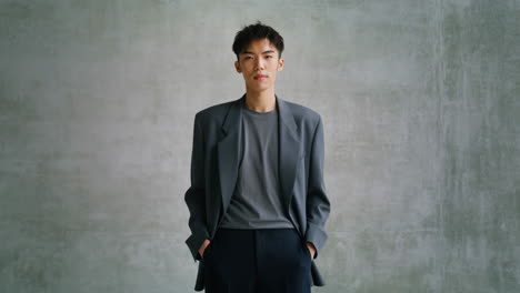 portrait of young man in grey blazer against concrete wall