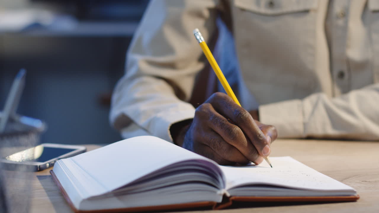 Close Up View Of Office Worker Writing Something With A Pencil In The Notebook In The Office At Night