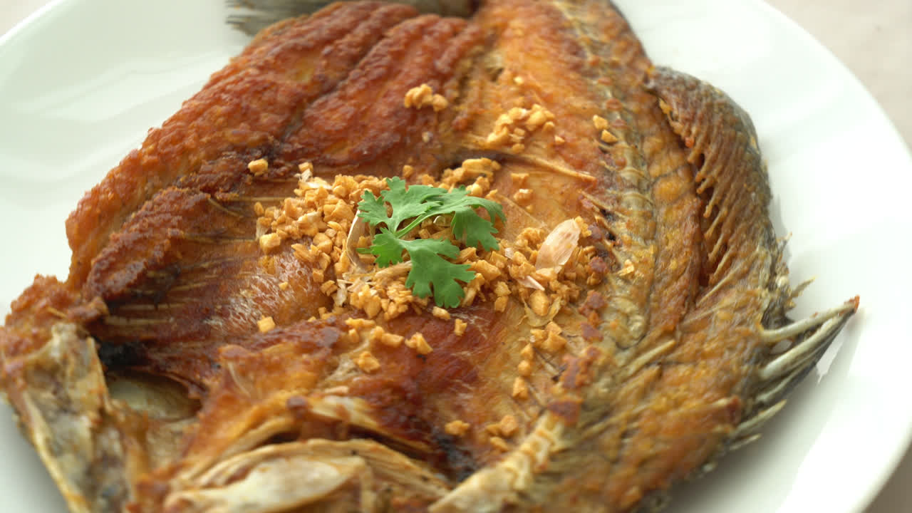 접시에 마늘을 얹은 농어 튀김