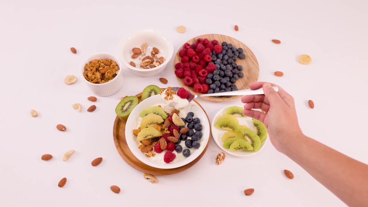 Seseorang Menyendok Mangkuk Yogurt Sehat dengan Buah Segar dan Kacang-kacangan