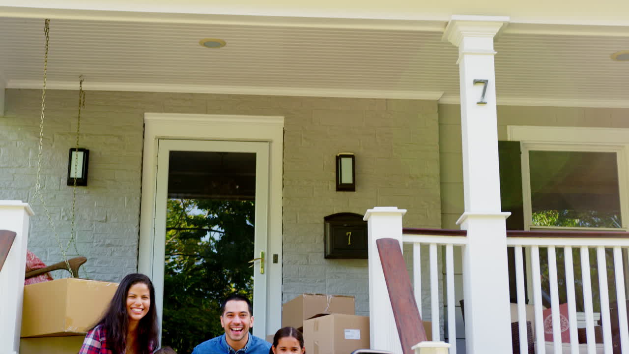 familia sentada en los escalones de la nueva casa en el día de mudanza