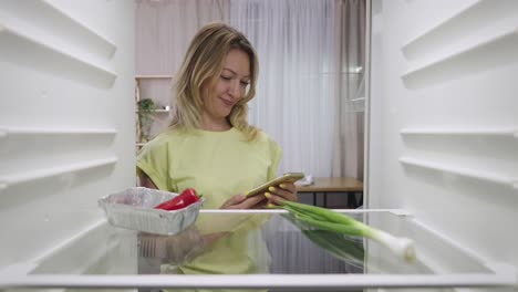 woman checking fridge for ingredients