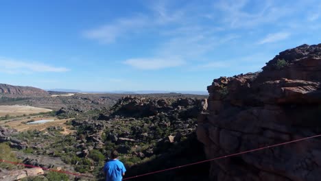 male highliner sitting on a rope over rocky mountains 4k