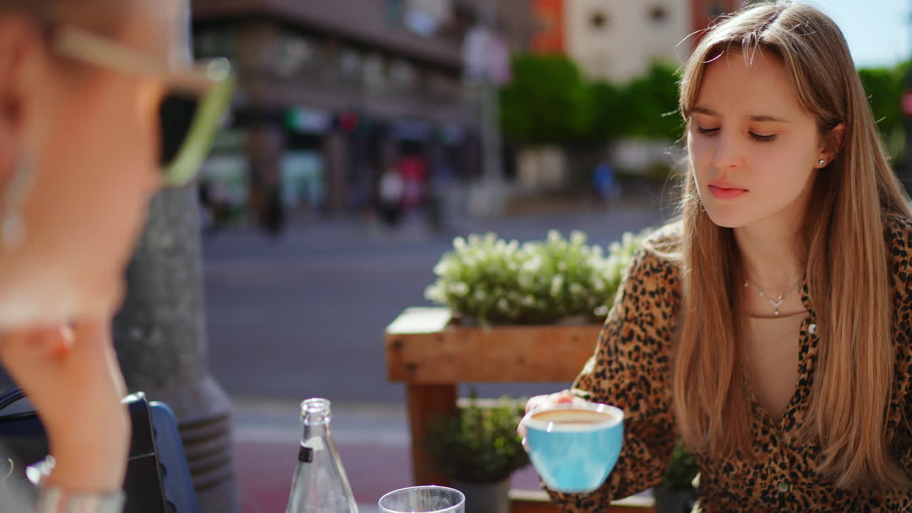 두 명의 여성이 야외 카페에서 대화를 나누고 있습니다.