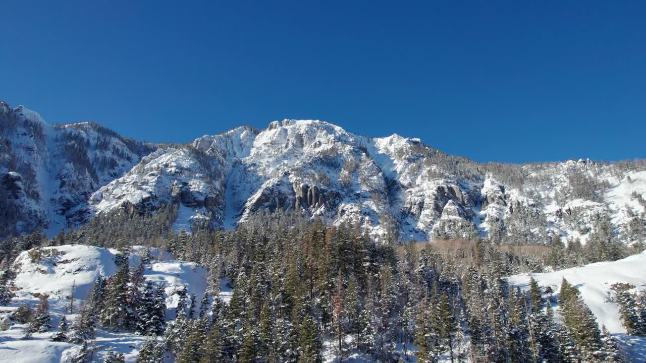 Ripresa con drone di cieli perfettamente azzurri e un fianco di montagna innevato.