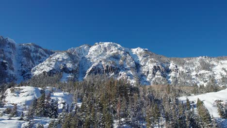 Drone-shot-of-perfectly-blue-skies,-and-a-snowy-mountainside