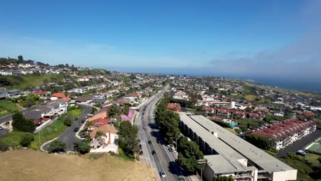 Cars-driving-through-residential-neighborhood-in-Southern-California-with-homes-and-ocean-in-background