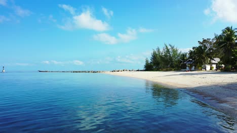 Blue-sea-water-reflecting-bright-sky-with-white-clouds-on-shore-of-tropical-island-with-sandy-exotic-beach-in-Thailand