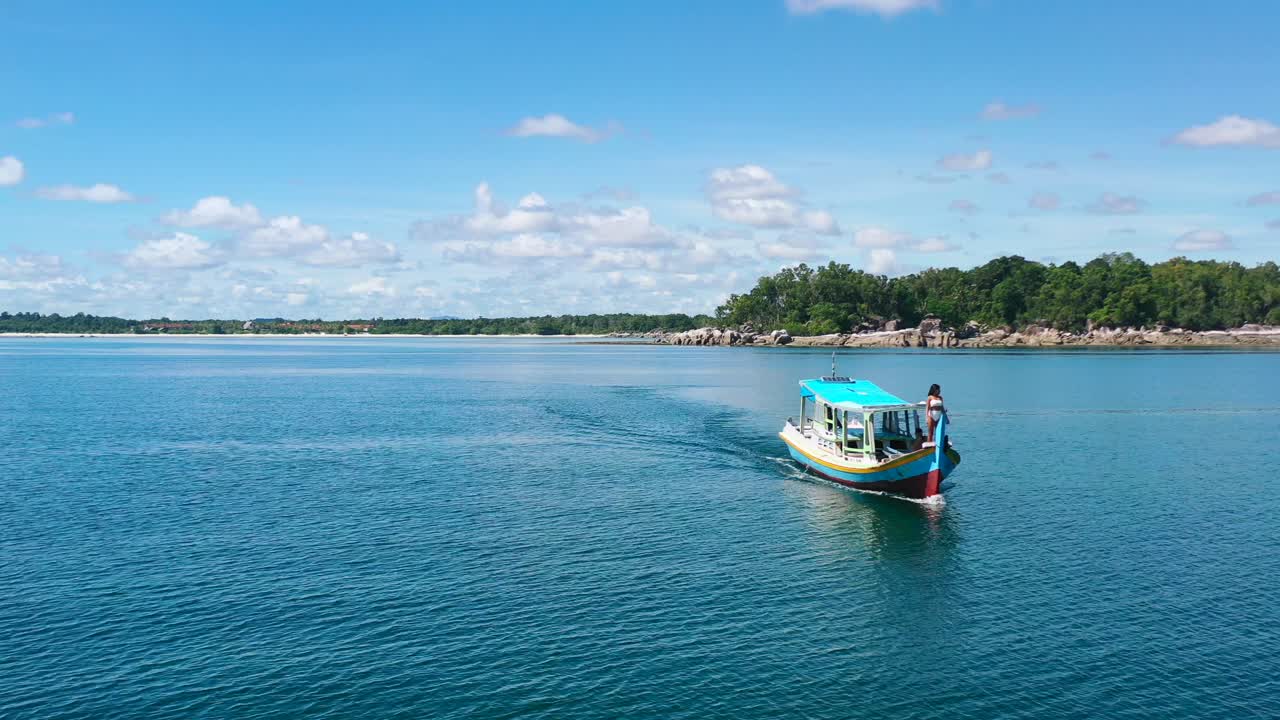 antena de una joven asiática parada frente a un bote en aguas tropicales de belitung indonesia