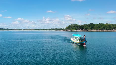 aerial-of-young-asian-girl-standing-on-front-of-boat-in-tropical-waters-of-belitung-indonesia